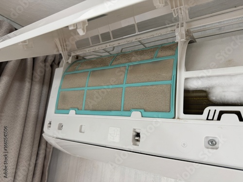 Close up of an air conditioner with a clogged dusty filter and ice formation inside, showing poor maintenance and risk to health and efficiency.