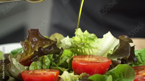 Pouring Olive Oil Over A Fresh Green Salad With Tomatoes