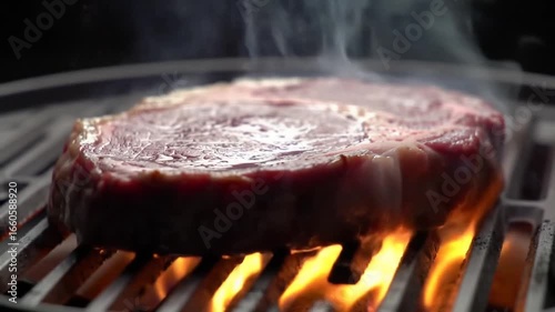 Prime Ribeye Steak Sizzling on a Grill Flames and Smoke