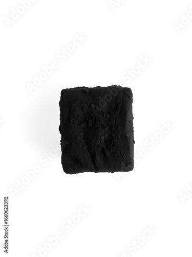Single black coal briquet or briquette over white background