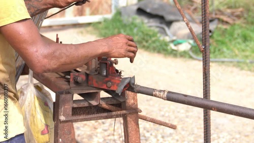 Construction worker bending steel rebar at building site for concrete structure.