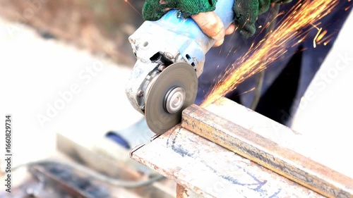 Construction worker cutting steel rebar with angle grinder at building site