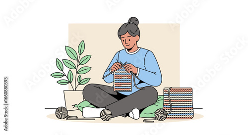 A woman sits cross-legged, knitting a colorful piece of fabric, relaxed and focused.