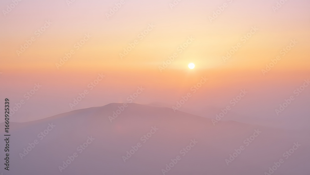 Fototapeta premium Serene sunrise over a misty mountain landscape with soft pastel colors creating a tranquil and atmospheric scene