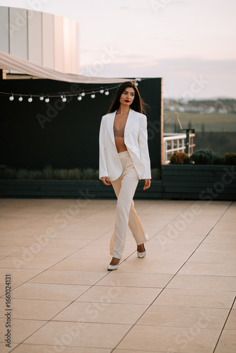 Fotografie Model walking elegantly on rooftop during sunset wearing stylish outfit