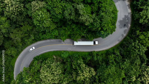 Fototapeta Naklejka Na Ścianę i Meble -  Aerial view semi truck trailer cargo on mountain curve road, Semi truck trailer cargo business logistic transportation on green forest road curve, Semi truck delivery asphalt road green forest tree.