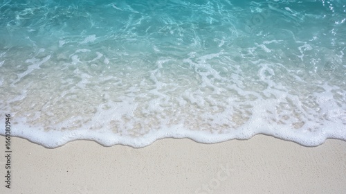 A beach with white waves and clear blue water.