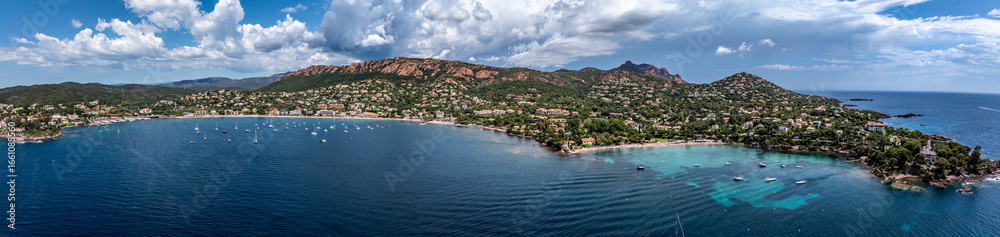 Fototapeta premium panoramic aerial landscape view of French Riviera coastline along Agay Bay in Saint-Raphaël with Plage d'Agay and Plage de La Baumette, many boats anchored in bay, wooded hilly landscape in background