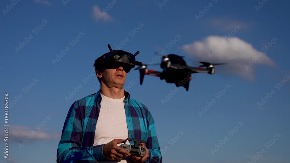 Man piloting drone with fpv goggles and handheld controller against ...