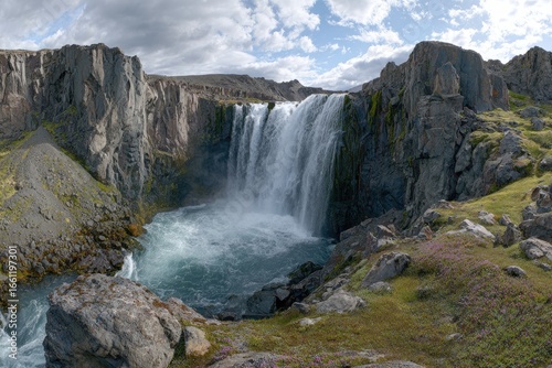 Majestic waterfall cascading into a rocky basin, surrounded by rugged mountains