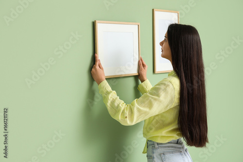 Young woman hanging picture...