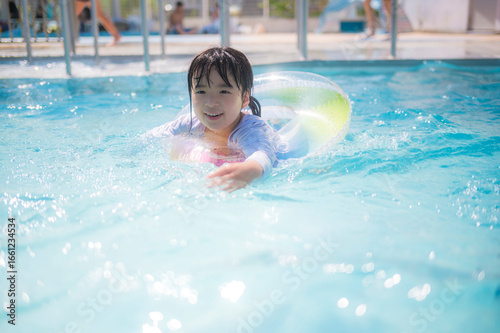 浮き輪でプールに浮かぶ女の子