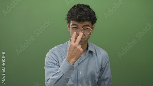 Foto Man in glasses squints and points finger sternly at camera in studio wearing blue shirt; accusation