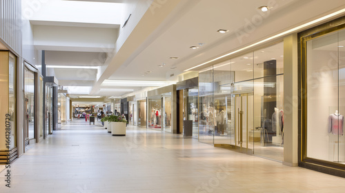 Modern shopping mall interior featuring a wide empty corridor with polished floors and soft lighting.