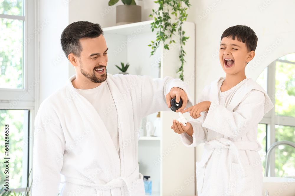 Fototapeta premium Happy father and his little son with bottle of shaving foam in bathroom