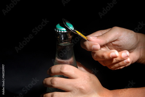 Cuadro en lienzo Female hand opening bottle using metal opener with isolated black background