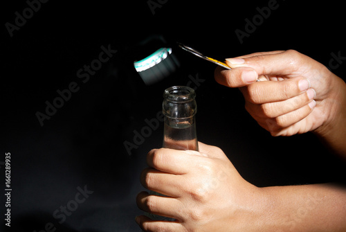 Quadro su tela Female hand opening bottle using metal opener with isolated black background