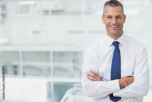 Fotografie Mid-adult man standing arms crossed in modern office wearing navy tie and weddin