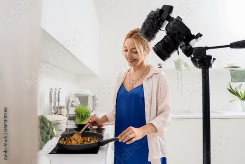 Mature woman frying vegetab...