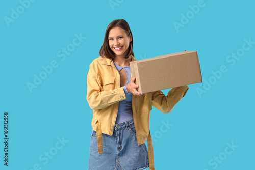 Beautiful young happy woman with parcel box on blue background