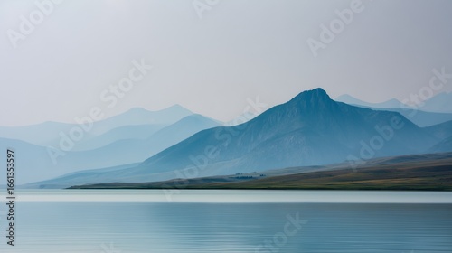 Minimalist landscape with distant low mountain range in soft gray outlines reflected on a calm gray-blue lake, 70% water, thin strip of pale sky, smooth gradients, no elements
