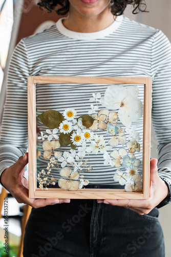 Woman holding a pressed flower frame made at a craft workshop