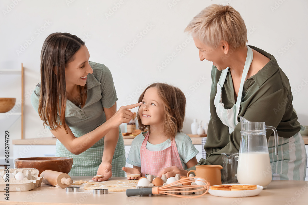 Cute little girl with her mother and granny making cookies in kitchen Cute little girl with her mother and granny making cookies in kitchen