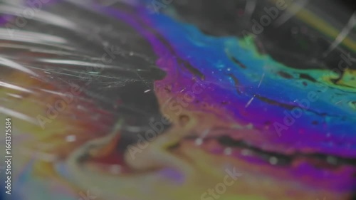 Close-up of a vibrant iridescent surface with swirling rainbow colors and abstract patterns.