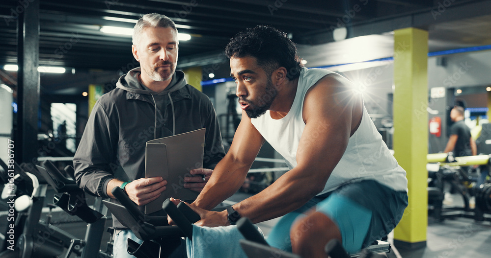 Obraz premium Exercise bike, man and personal trainer in gym for fitness, help or workout for health. Cycling, coach and training in sport club with stationary bicycle for spin class, cardio or wellness with flare