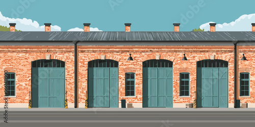 Facade of a vintage industrial brick building with large teal arched garage doors and a metal roof.