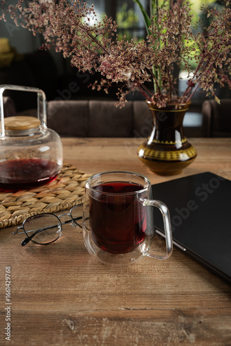 Cozy tea time at home with herbal brew, glasses, and a journal on a wooden table