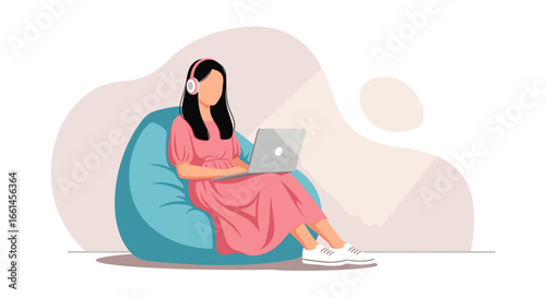 Young woman in a pink dress, wearing headphones and working on a laptop while comfortably seated on a bean bag chair. Ideal for remote work, study, or leisure concepts.