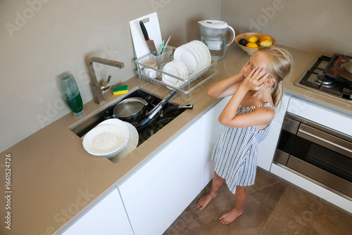 Tired girl staring at messy kitchen sink