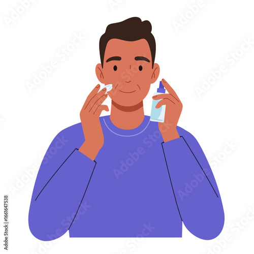 A modern man with a healthy complexion meticulously applies a refreshing facial toner to his cheek with a cotton pad, showcasing an essential daily skincare routine.