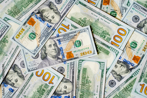a lot of money banknotes of one hundred 100 American dollars lie on the table in different order, mixed and piled up, the background is piled up with money American green dollars with the image of the