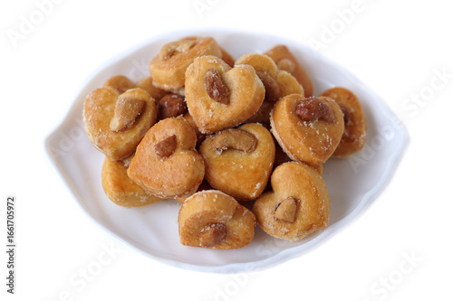Delicious cashew nut cookies, also known as Singapore cookies, arranged on a white plate. Heart-shaped, golden brown, and sprinkled with sugar, perfect for snacks, desserts, or bakery promotion.