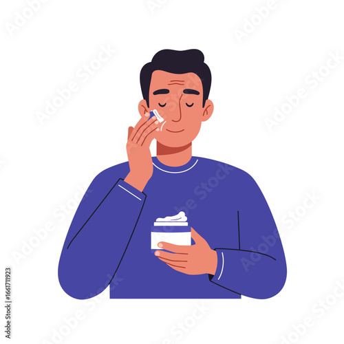 A contented young man applies nourishing facial cream to his cheek, engaging in a daily self-care and grooming routine for healthy skin.