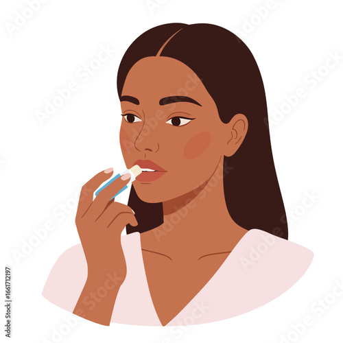 A beautiful young woman with dark skin applies moisturizing lip balm to her lips, practicing daily self-care and beauty routine.