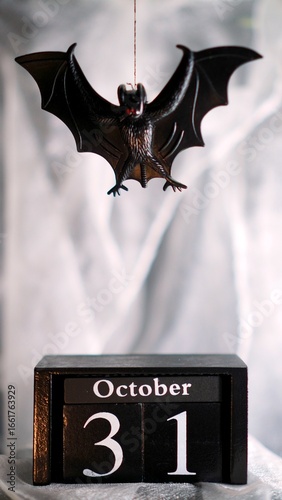Halloween bat hanging from a thread over a calendar indicating october 31st, with a smoke effect, suitable for posters, invitations to halloween parties and social networks