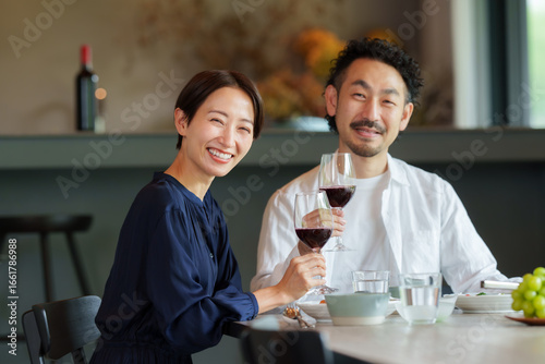 モダンなリビングダイニングで赤ワインを飲む夫婦