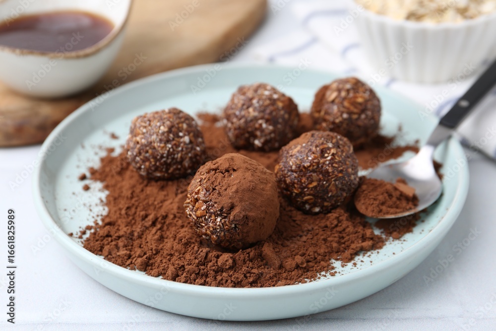 Delicious homemade candies with cocoa powder on white table, closeup Delicious homemade candies with cocoa powder on white table, closeup