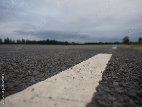 Close-up of asphalt road with white line, low angle view symbolizing travel, journey and transportation.