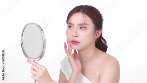 Young woman looking at her skin in the mirror with a concerned expression, assessing her complexion representing concerns like skincare, skin problems, or beauty routines.