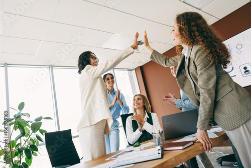 Fototapet Professional team celebrating success with a high five in a contemporary office