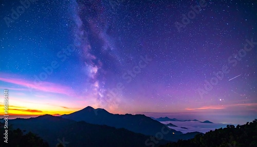 Panoramic view of the Milky Way over mountains at dawn