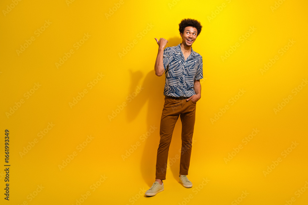 Fototapeta premium Charismatic young man in stylish summer wear gesturing optimistically against a vibrant yellow background