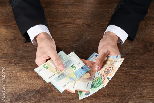 Wallpaper Mural Man with euro banknotes at wooden desk, above view Torontodigital.ca