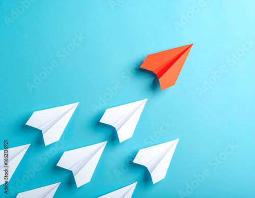 A red paper airplane leading a group of white paper airplanes, symbolizing leadership and individuality.