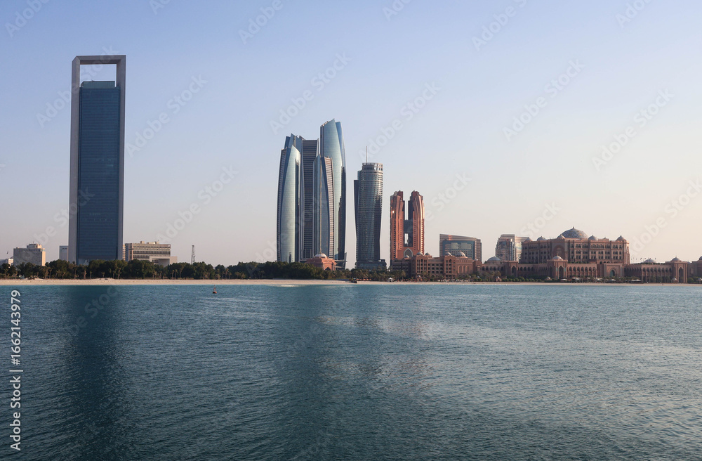 Obraz premium Modern Abu Dhabi skyline with high-rise towers, wide streets, and city lights showcasing the UAE’s capital’s urban beauty.
