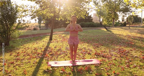 Fit sportswoman practicing yoga. Happy young woman outdoors in autumn park. Slow motion. 